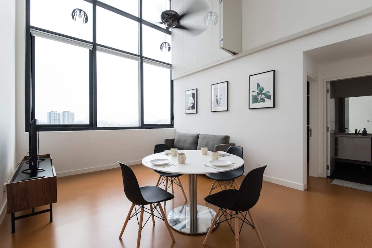 A modern dining area with a round table, black chairs, and a ceiling fan.