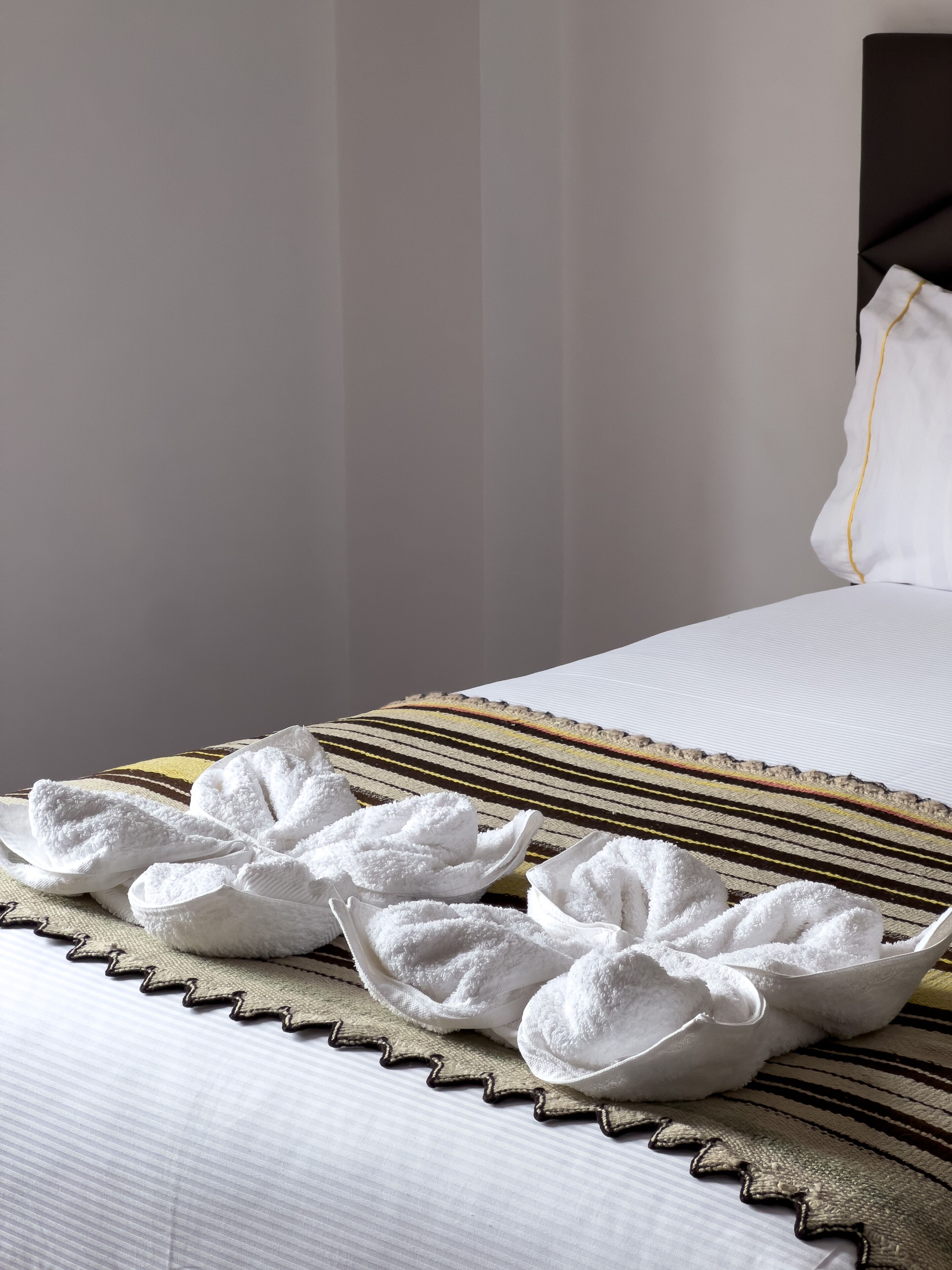 A neatly made bed with a striped blanket and a pillow with a yellow border.