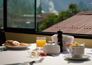 A breakfast table with a croissant, orange juice, and a fruit bowl. - Hotel Andes Urubamba By Ämak (Urubamba)