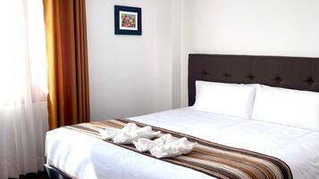 A neatly made bed with a striped blanket, a dark headboard, and a framed picture on the wall.