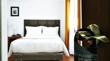 A hotel room with a bed, a bedside table, and a door with a sign that reads "PLEASE DO NOT DISTURB".