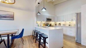 Une cuisine moderne dotée d’un îlot central, de tabourets de bar et d’un coin repas avec une table et des chaises.