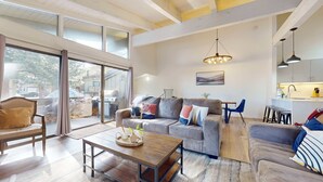 Un salon moderne avec un canapé gris, une table basse en bois et un coin repas avec des chaises bleues.