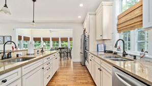 A modern kitchen with white cabinetry, granite countertops, and stainless steel appliances.