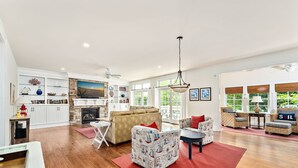 A spacious living room with a fireplace, a large window, and a cozy seating area.