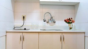 Una cocina con armarios blancos, un lavamanos de acero inoxidable y un florero con flores en la encimera.