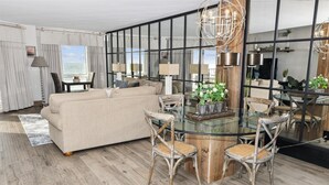 Un salon moderne avec une table à manger en verre, un canapé beige et des chaises au style rustique.
