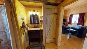 Een houten cabin met een badkamer, een bank en een televisie.