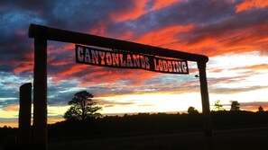 A sign reading "CANYONLANDS LODGING" against a sunset sky.