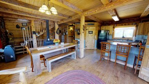 A rustic wooden cabin interior with a dining area, kitchen, and a staircase leading to a loft. - Canyon View Family Lodge (Monticello)