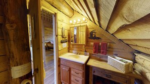 Een houten badkamer in een chalet, met een wastafel, spiegel en handdoekhouder.