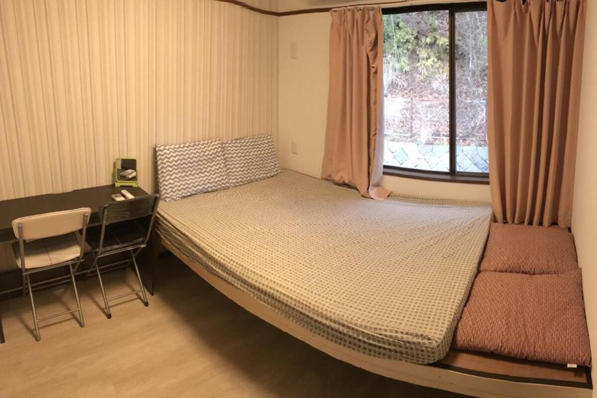 Een kleine kamer met een bed, een bureau en een stoel.