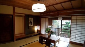 A traditional Japanese room with tatami flooring, a low wooden table, and a hanging light fixture. - Kinkaku Ryokan (Kyoto)