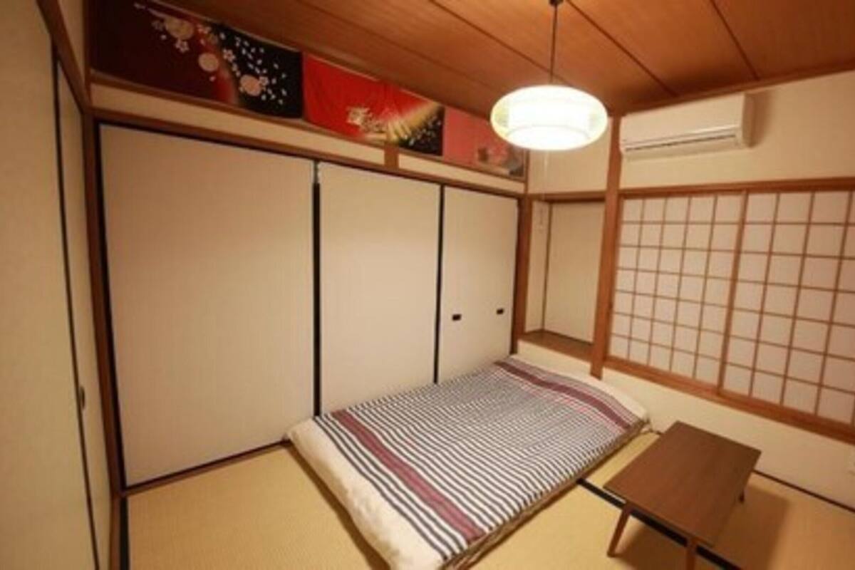 Een traditionele Japanse kamer met tatami vloerbedekking, een lage houten tafel, een futon bed, schuifdeuren en een shoji scherm.