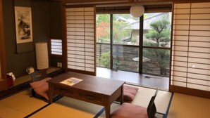 A traditional Japanese room with tatami flooring, a low table, and shoji screens. - Kinkaku Ryokan (Kyoto)