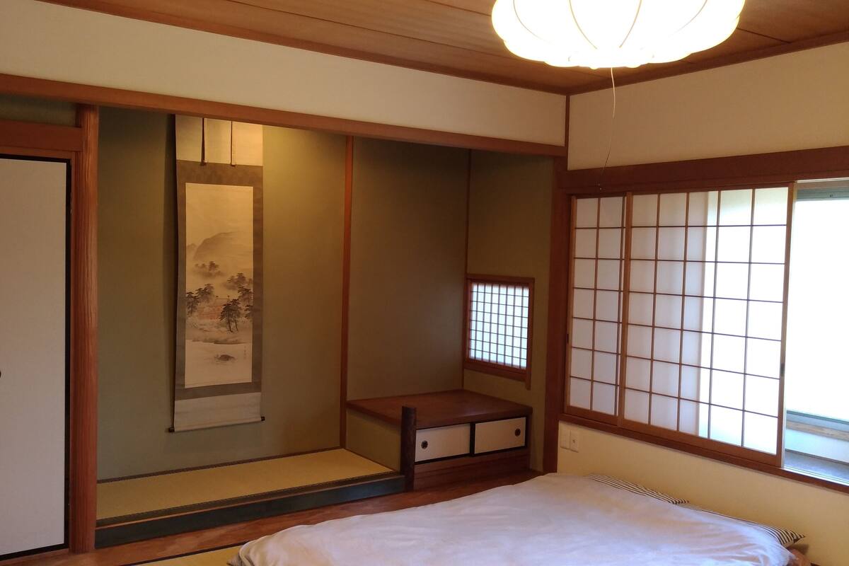 Een traditionele Japanse kamer met tatami vloerbedekking, een shoji scherm, een glijdende deur en een bed met een witte matras.