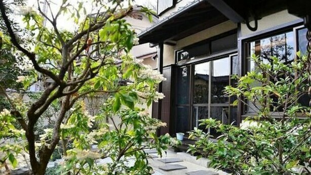 A traditional Japanese-style building with a wooden exterior, large windows, and a stone pathway leading to the entrance. - Kinkaku Ryokan (Kyoto)