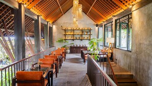 A spacious interior with a high ceiling, wooden beams, and a central staircase. - Purana Suite Ubud (Ubud)