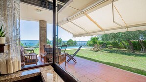Un balcon spacieux offrant une vue sur une piscine et une zone verdoyante avec des arbres.