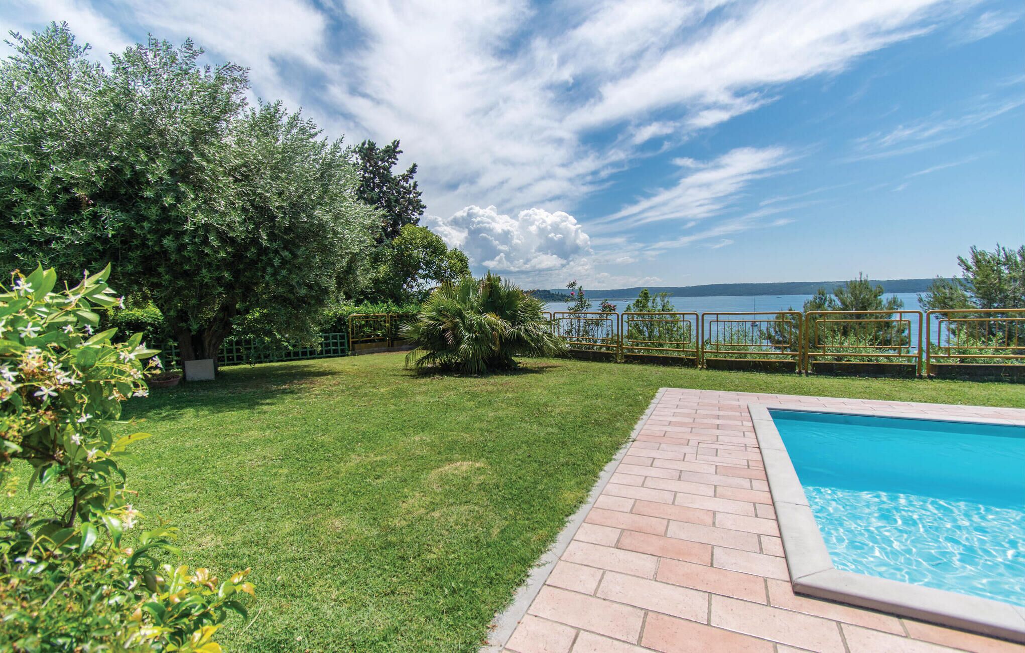 A backyard with a swimming pool, a grassy lawn, and a view of a lake.
