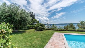 Un jardin avec une piscine, une pelouse verdoyante et une vue sur un lac.
