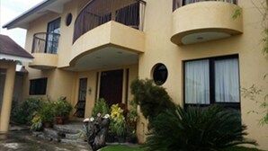 A multi-story building with balconies, a central entrance, and potted plants around the entrance. - Palm Seaside Inn and Beach Resort (Medellin)
