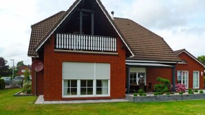 Een twee verdiepingen tellend huis met een rode bakstenen gevel, een witte garagepoort en een klein balkon met een witte balustrade.