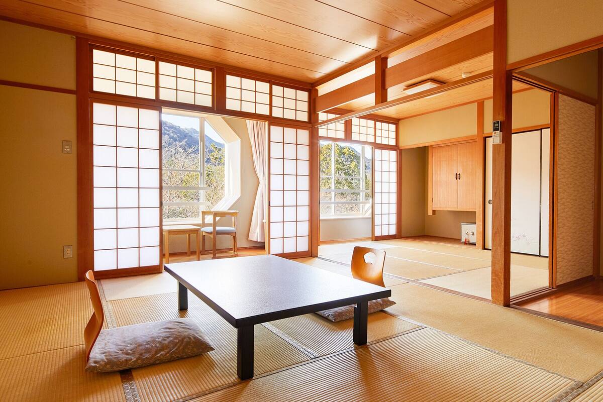 A traditional Japanese room with tatami flooring, a low table, and sliding doors.