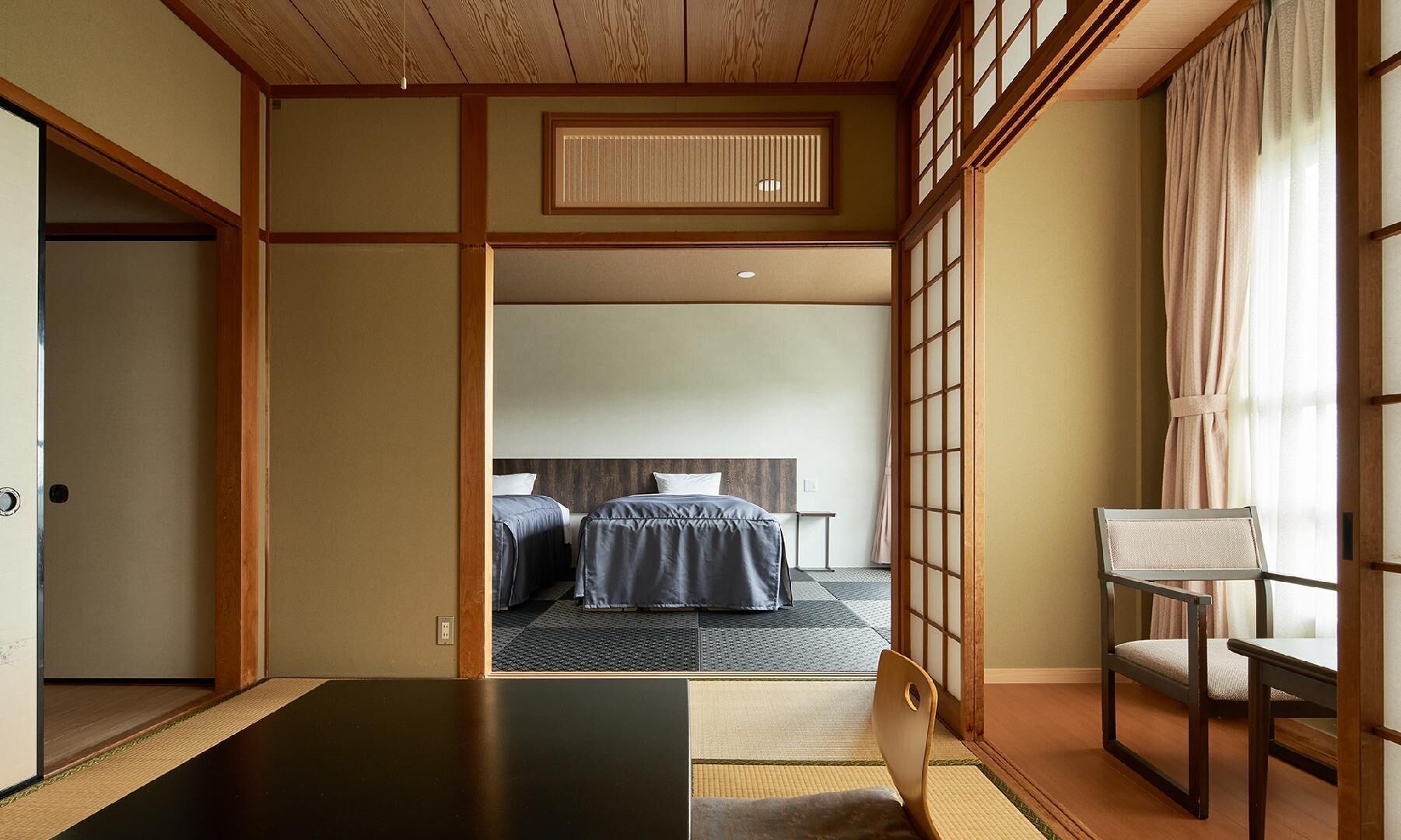 Una habitación tradicional japonesa con suelo de tatami, techo de madera bajo y puertas correderas.