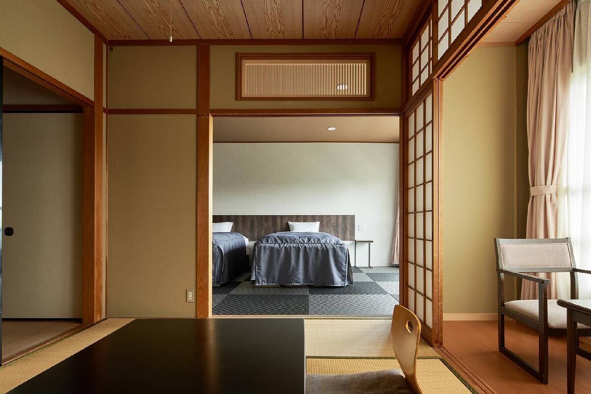 A traditional Japanese-style room with tatami flooring, a low wooden ceiling, and sliding doors.