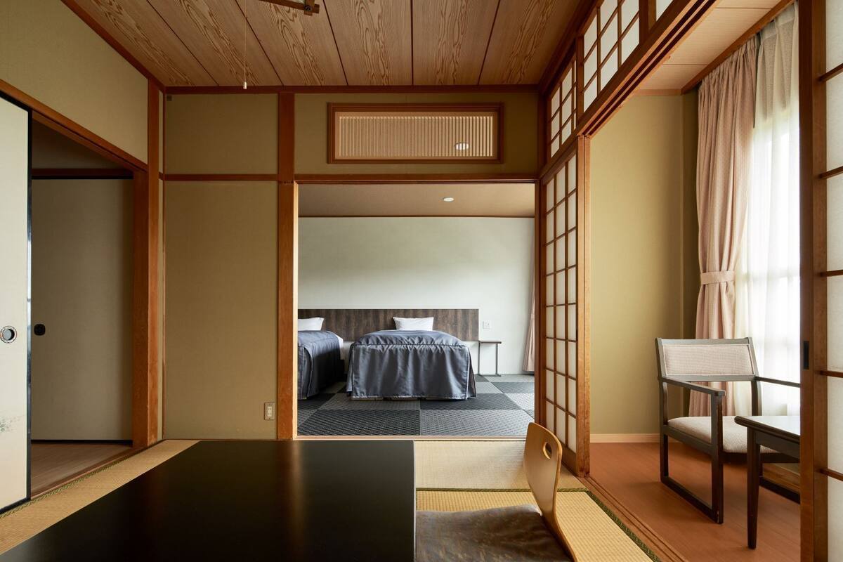 A traditional Japanese-style room with tatami flooring, a low wooden ceiling, and sliding doors.