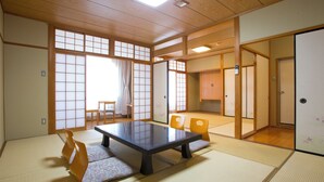 Ett traditionellt japanskt rum med tatamimattor på golvet, ett lågt bord och skjutdörrar.