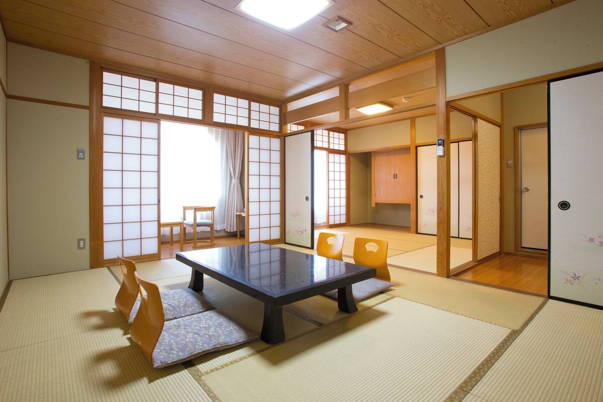 A traditional Japanese room with tatami flooring, a low table, and sliding doors.