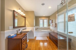Un baño con tocador de madera, un espejo grande, una bañera y una cabina de ducha de vidrio.