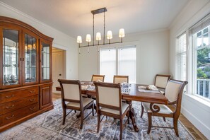 Un comedor con una mesa de madera, seis sillas, una araña y un aparador grande de madera.