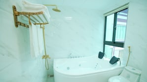 A bathroom with a freestanding bathtub, a toilet, and a towel rack with towels. - King's Hotel Yen Hoa (Hanoi)