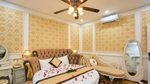 A luxurious bedroom with a tufted headboard, a large mirror, and a decorative bedspread. - King's Hotel Yen Hoa (Hanoi)