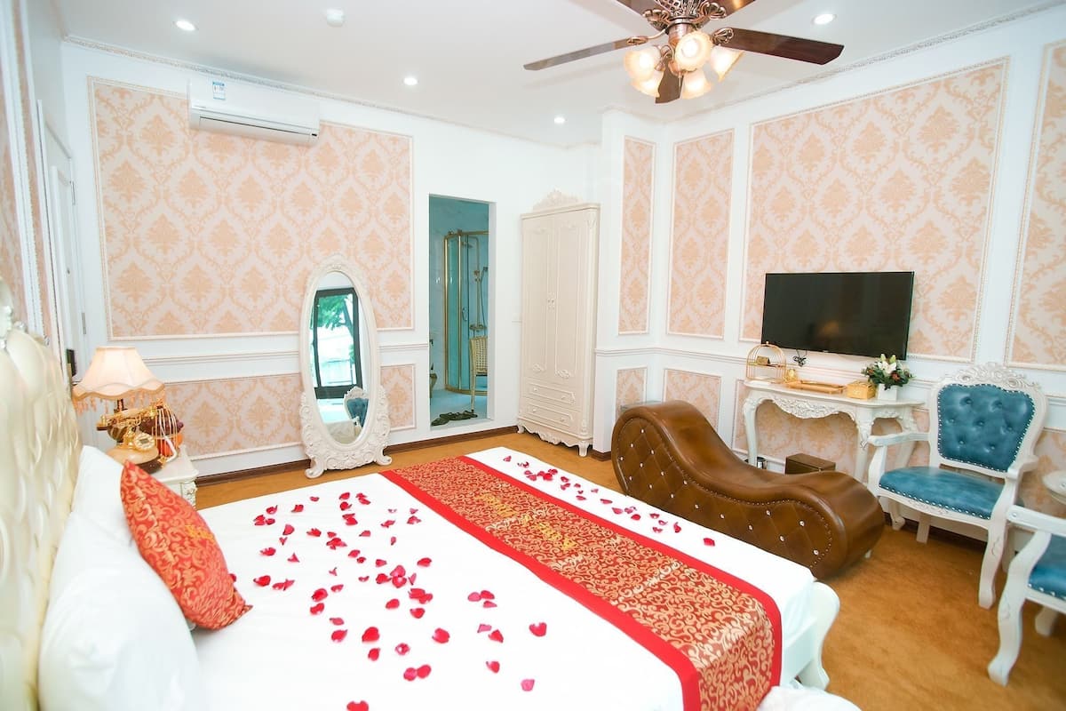 A hotel room with a bed, a television, a seating area, and a bathroom visible through an open door.