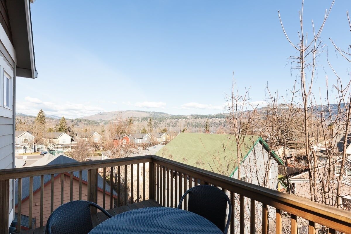 A balcony with a view of a residential area, including houses and a green field.