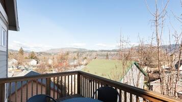 A balcony with a view of a residential area, including houses and a green field.