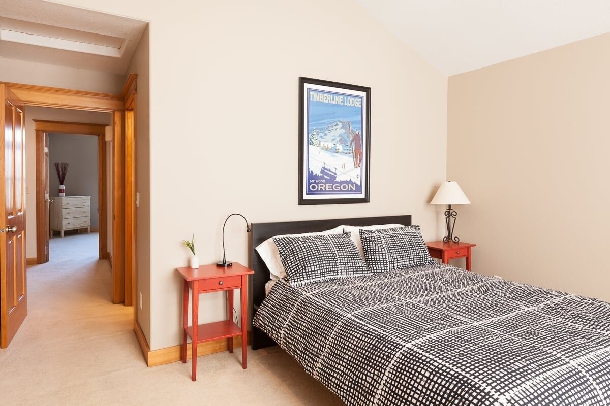 A bedroom with a bed, a nightstand, a lamp, and a poster on the wall.