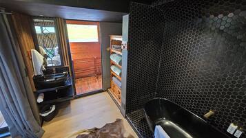 A modern bathroom with a large black bathtub, a wooden vanity, and a glass-enclosed shower area.
