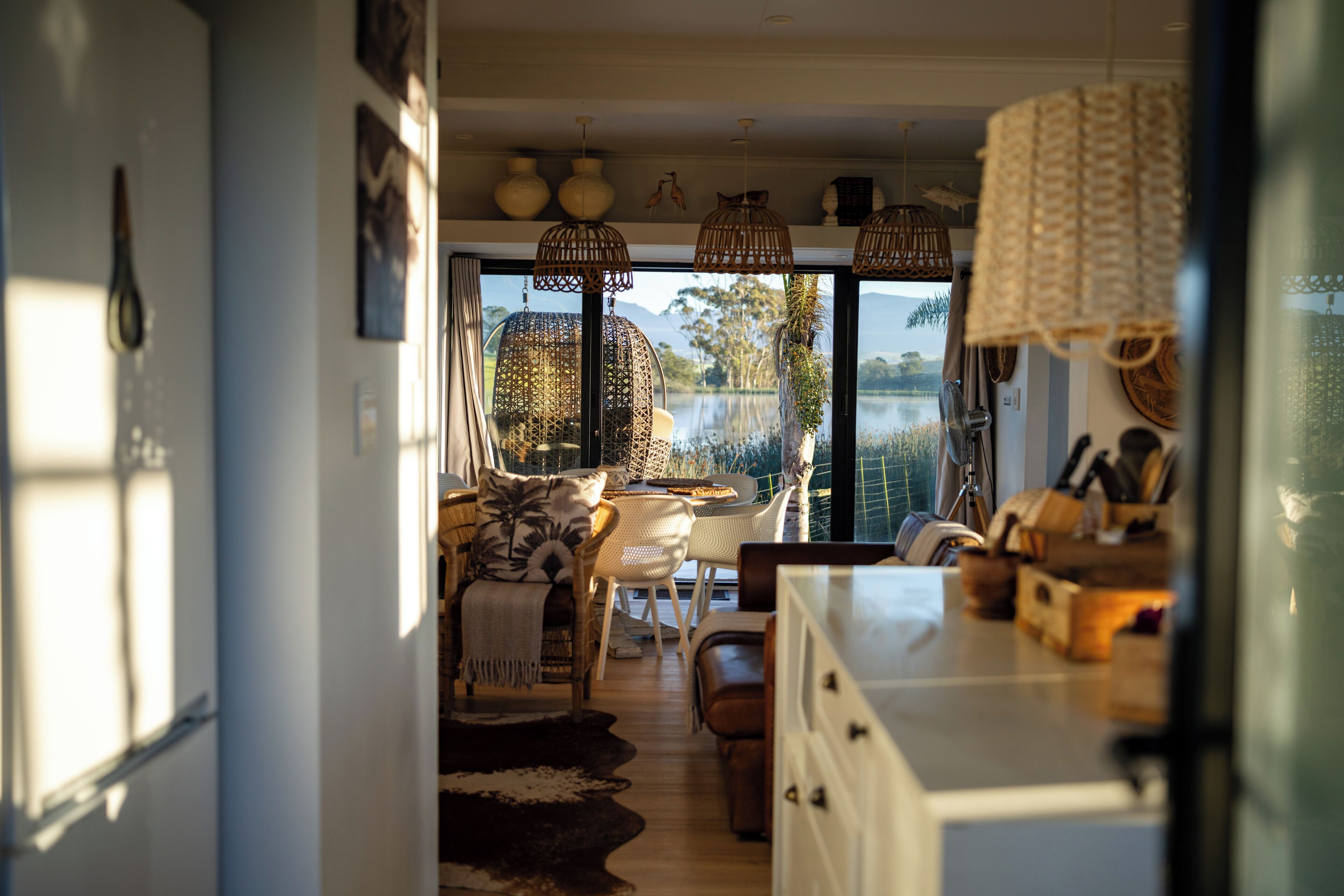 A modern interior with a dining area, large windows, and a view of a lake.