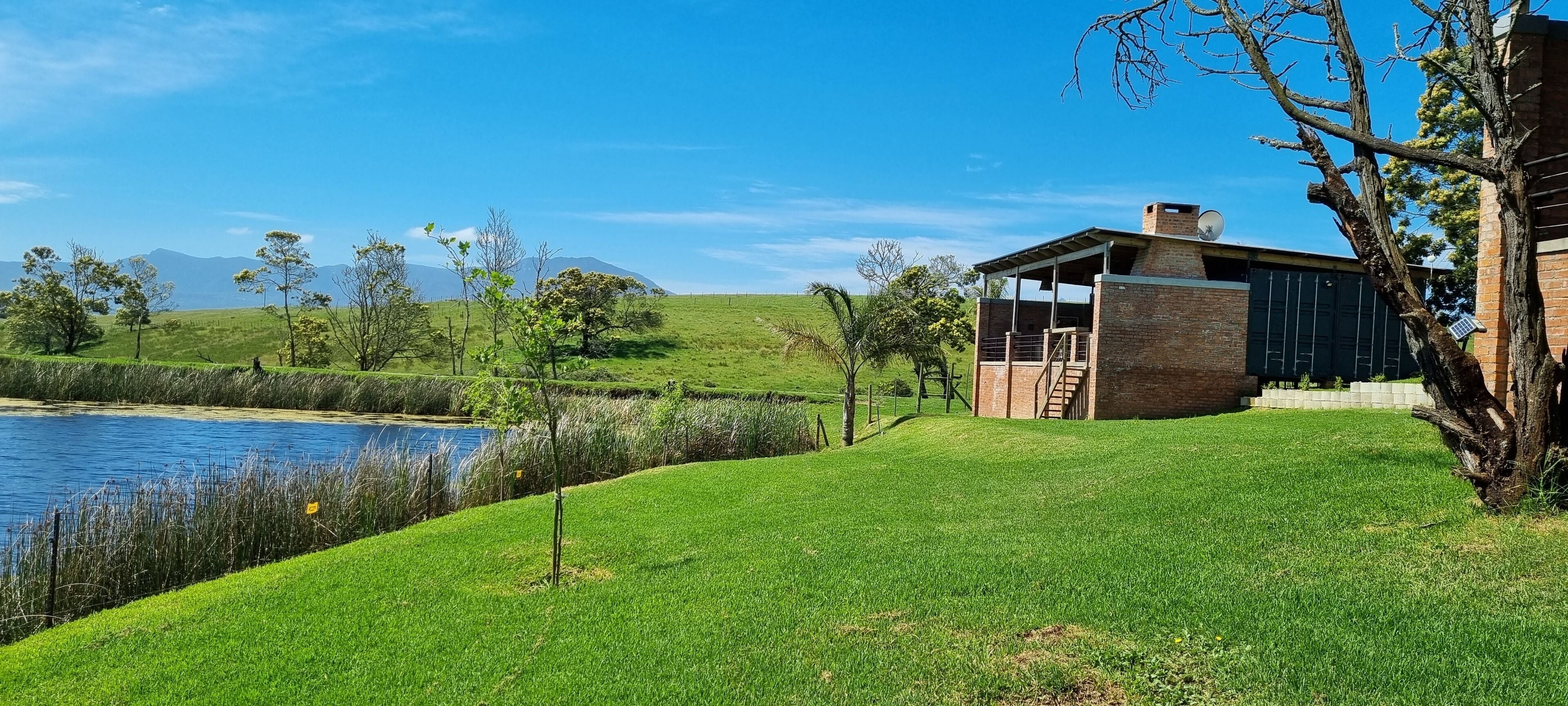 Una casa con fachada de ladrillo, un porche cubierto y una vista a un lago y montañas al fondo.