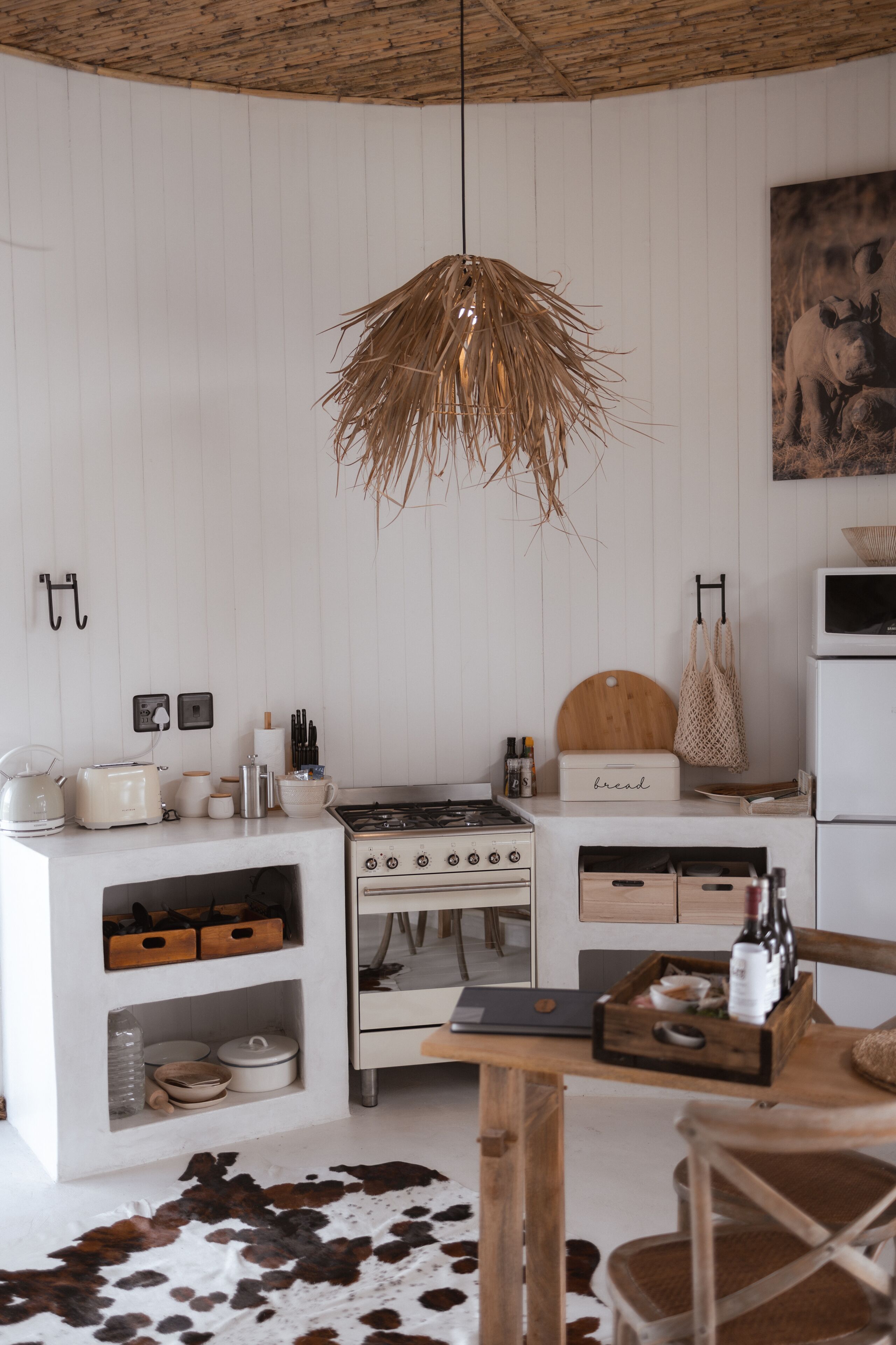 A modern kitchen with white cabinetry, a stove, and a hanging light fixture.
