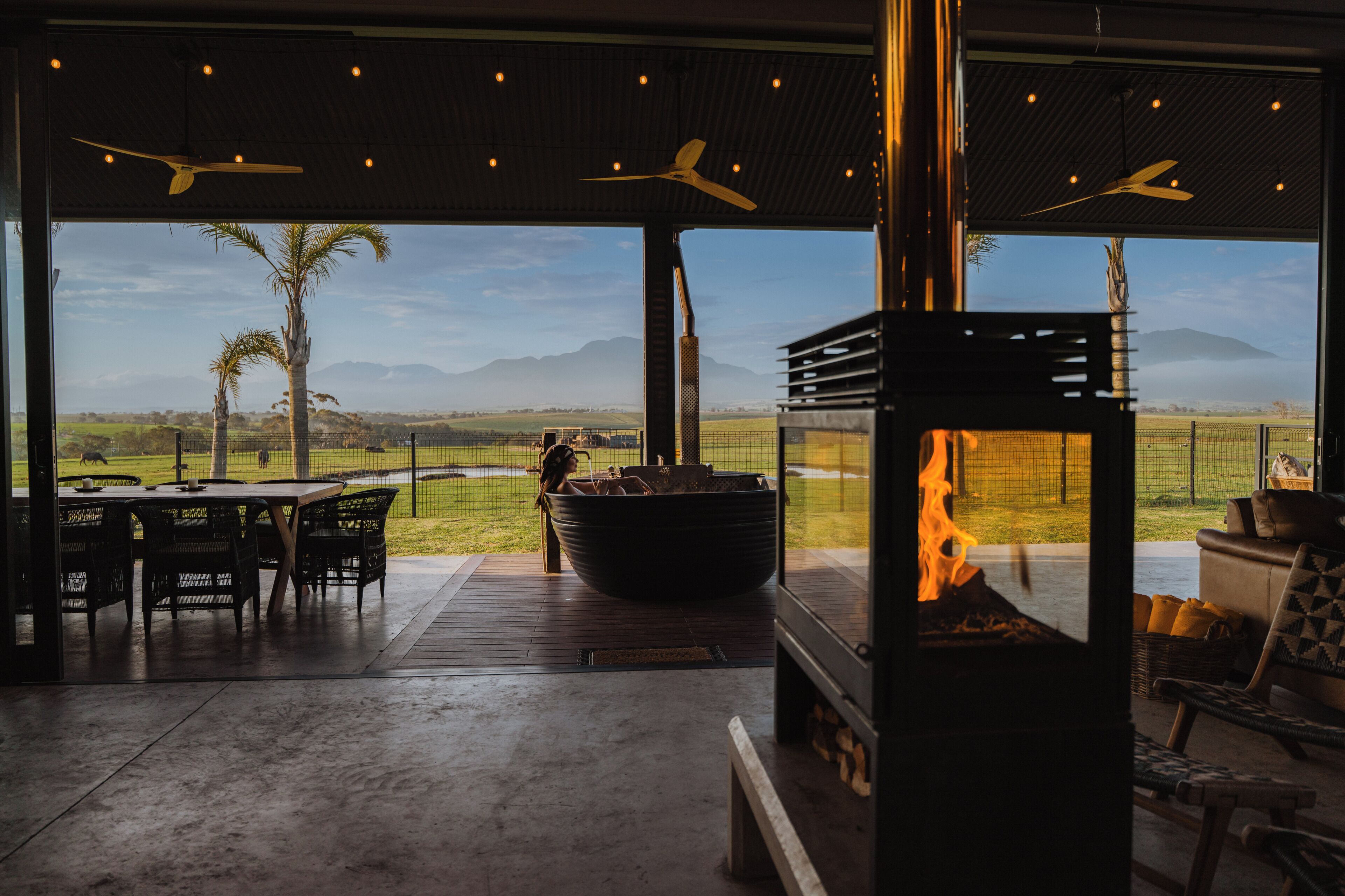 An outdoor patio with a fire feature, seating, and a view of the landscape.