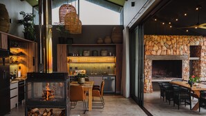Una cocina moderna con estufa de leña, comedor con sillas y chimenea de piedra.