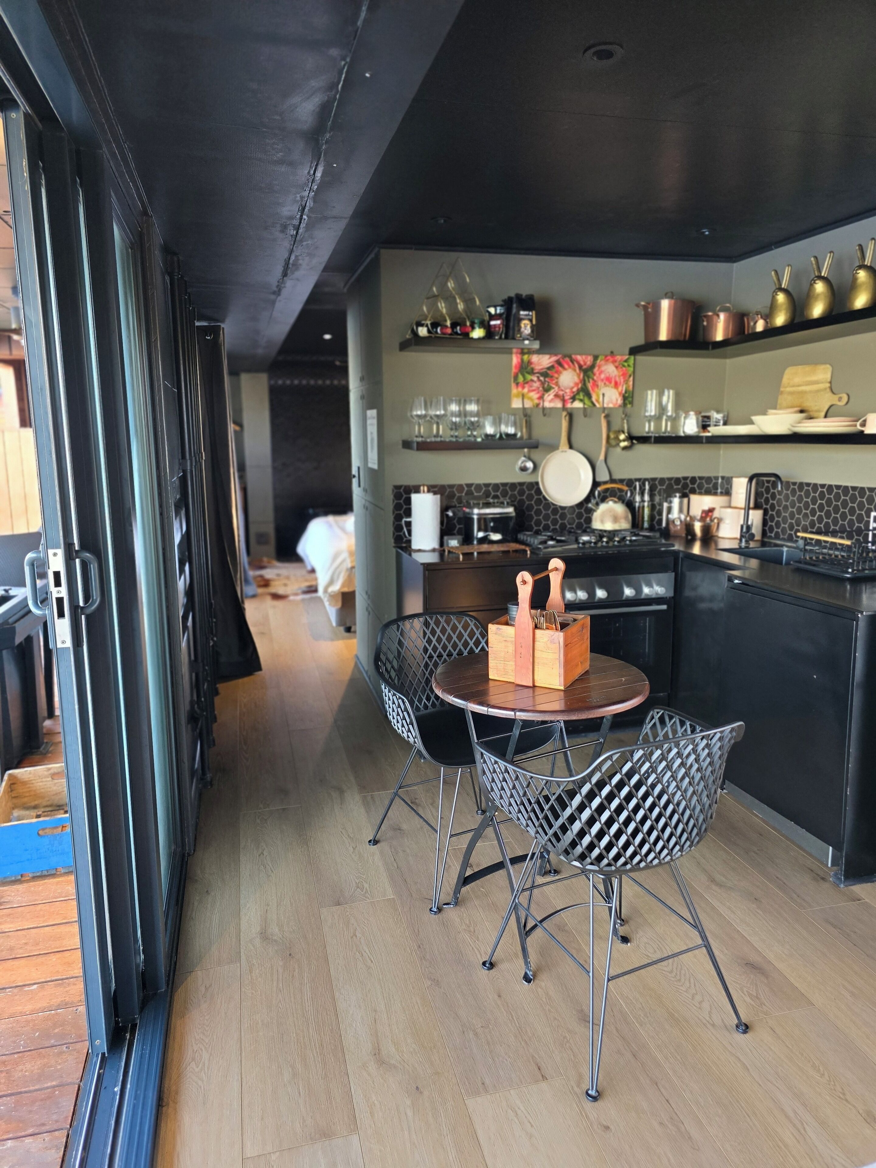 A modern kitchen with a central island, black metal chairs, and a dining table.