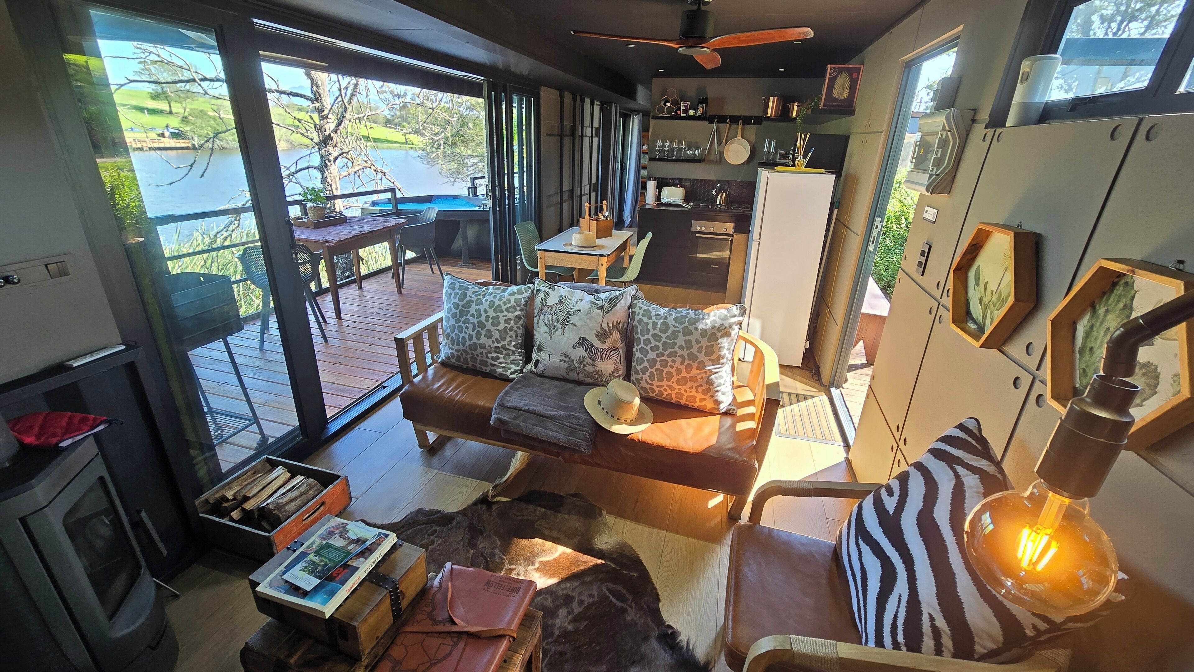 A spacious living area with a large window overlooking a scenic outdoor view, a cozy seating area with a sofa and a fireplace, and a kitchen with modern appliances.