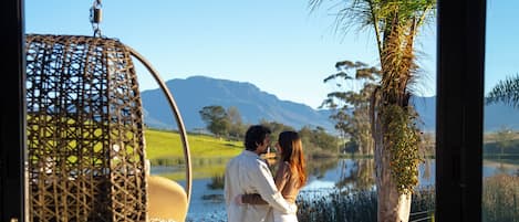 Una pareja de pie junto a una piscina con vistas a un lago y montañas.